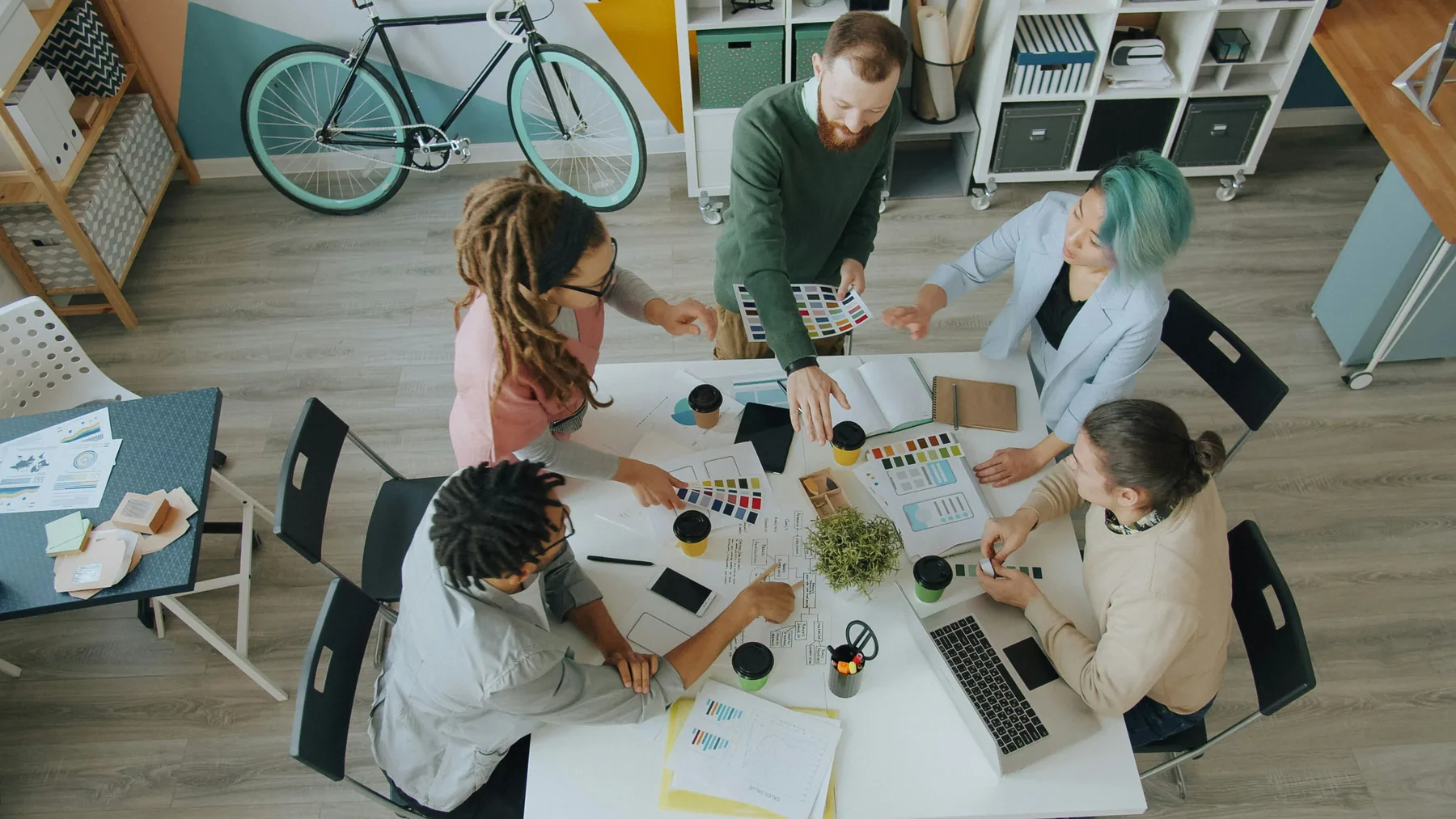 Colleagues collaborate around a table to review design ideas.